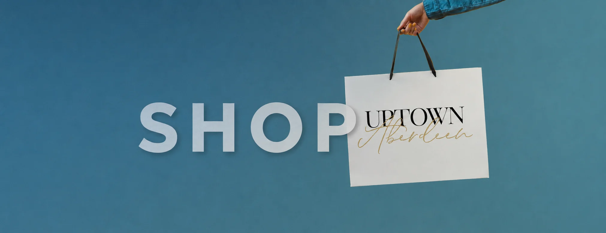 Shop Uptown Aberdeen: a hand holding an Uptown Aberdeen shopping bag